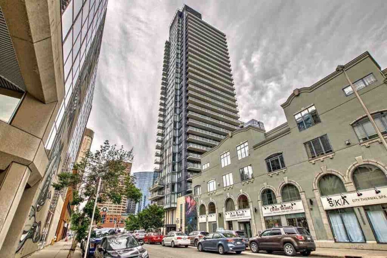 A city street with tall buildings, parked cars, and a spa named "City Thermal Spa".