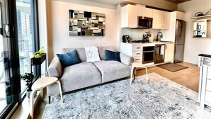 A modern apartment with a living room, kitchenette, and a large window. - Cozy DT Fantastic Amenities View Private Parking (Calgary)