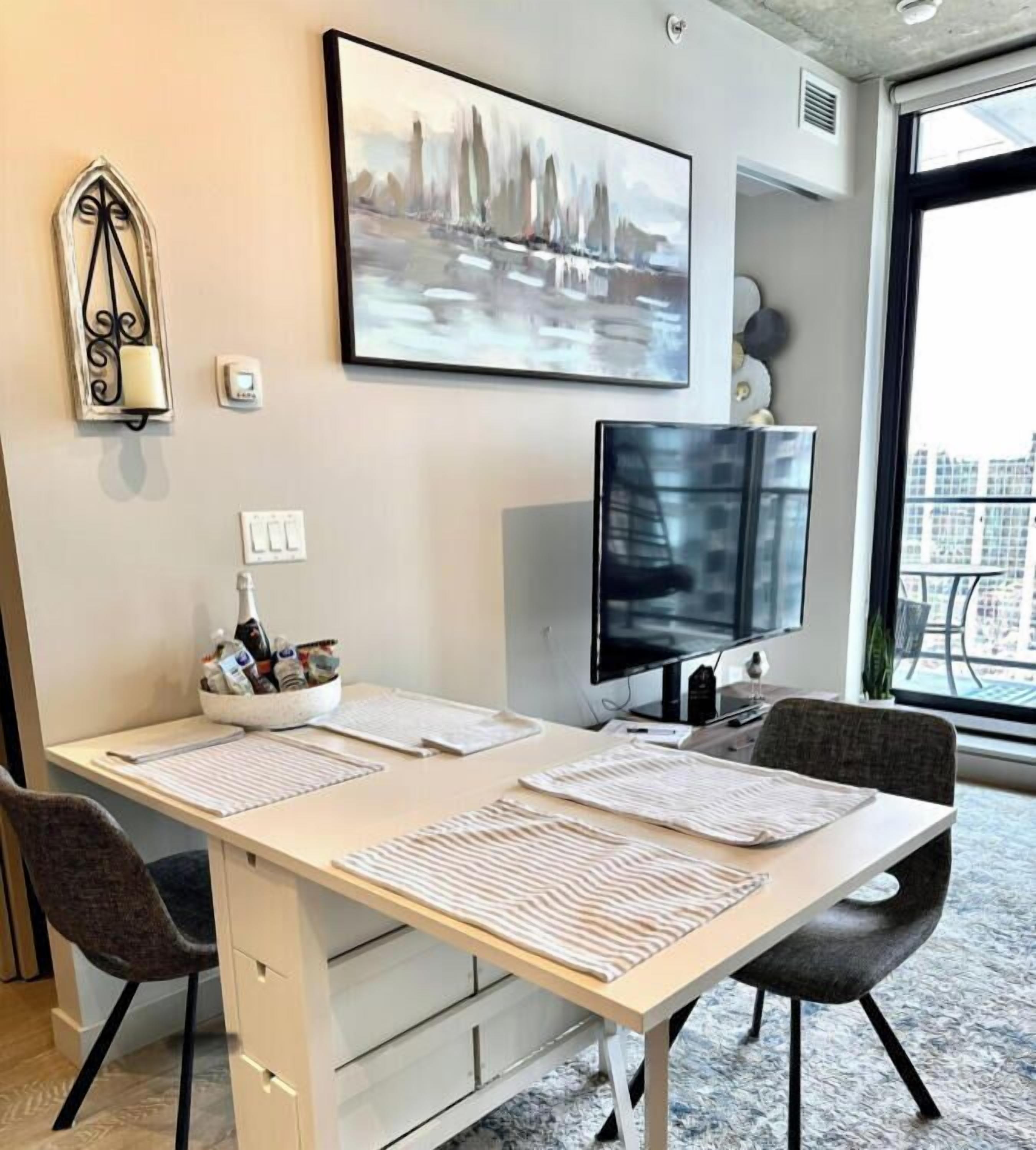Un espace de bureau moderne comprenant un grand bureau, deux chaises, un écran d’ordinateur et un tableau accroché au mur.
