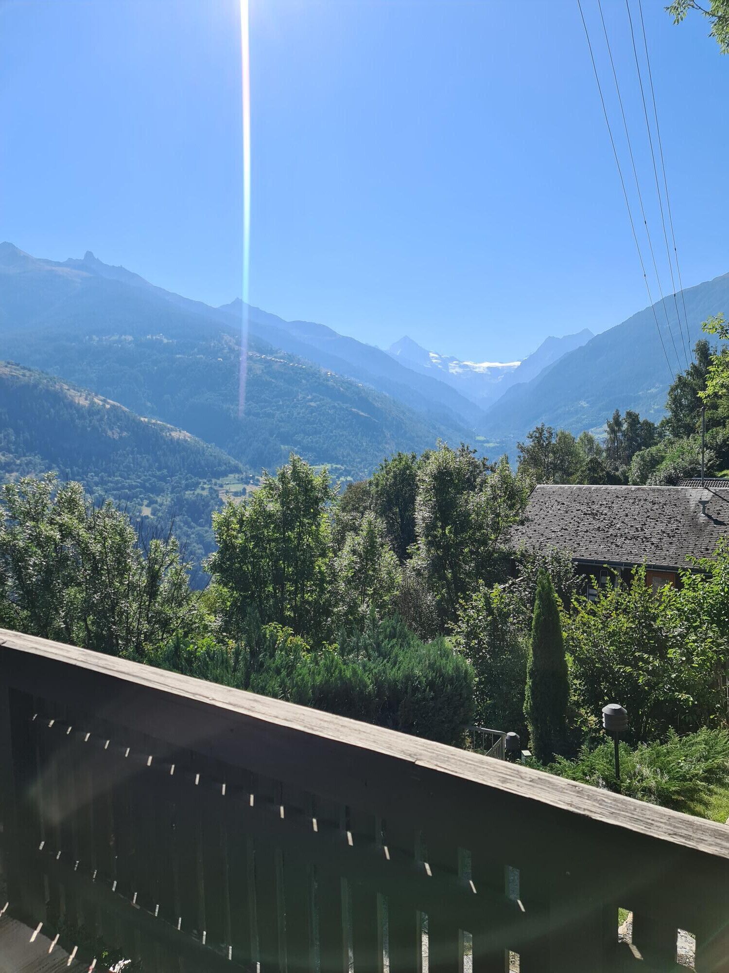 Vista panorámica desde un balcón con vistas a un paisaje montañoso bajo un cielo despejado.
