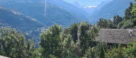 Ein malerischer Blick vom Balkon auf eine gebirgige Landschaft bei klarem Himmel.