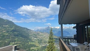 A balcony with a view of a mountainous landscape, a small table, and chairs. - Crêtes X2 232 - SUNNY apartment 6 pers (Veysonnaz)