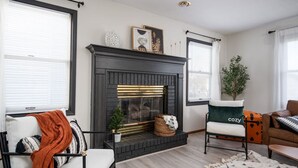 A living room with a fireplace, a sofa, a chair, and a small table. - `Corporate Elegance: Luxe Home in Grand Rapids` (Kentwood)