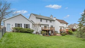A two-story house with a front deck and a small porch. - `Corporate Elegance: Luxe Home in Grand Rapids` (Kentwood)