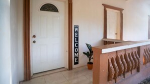 A reception area with a white door, a 'WELCOME' sign, a potted plant, and a decorative wall. - Eleven30 Luxury Apartments Studio 1-B. Cozy retreat in a lush local Negril area. (Negril)