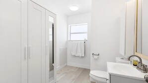 A modern bathroom with a toilet, sink, and a large mirror.