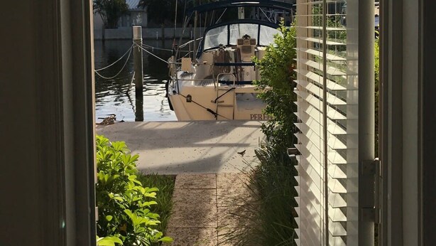 A view from a window overlooking a marina with boats docked, a pedestrian bridge, and a building with a sloped roof. - Waterfront Condo Near Las Olas and Beach (Fort Lauderdale)