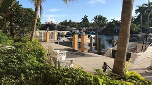 A marina with boats docked, palm trees, and a paved walkway with benches. - Waterfront Condo Near Las Olas and Beach (Fort Lauderdale)