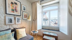 Ett mysigt rum med en soffa, ett litet bord och ett fönster med utsikt över en balkong.