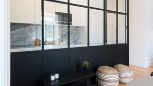 Una cocina moderna con encimera de mármol, armarios negros y un amplio ventanal.