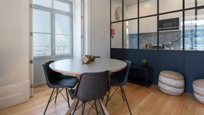 Una cocina moderna con una mesa redonda, sillas negras y un amplio ventanal.