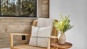 Ein Holzhocker mit Kissen und ein kleiner Tisch mit einer Vase mit Grünpflanzen.