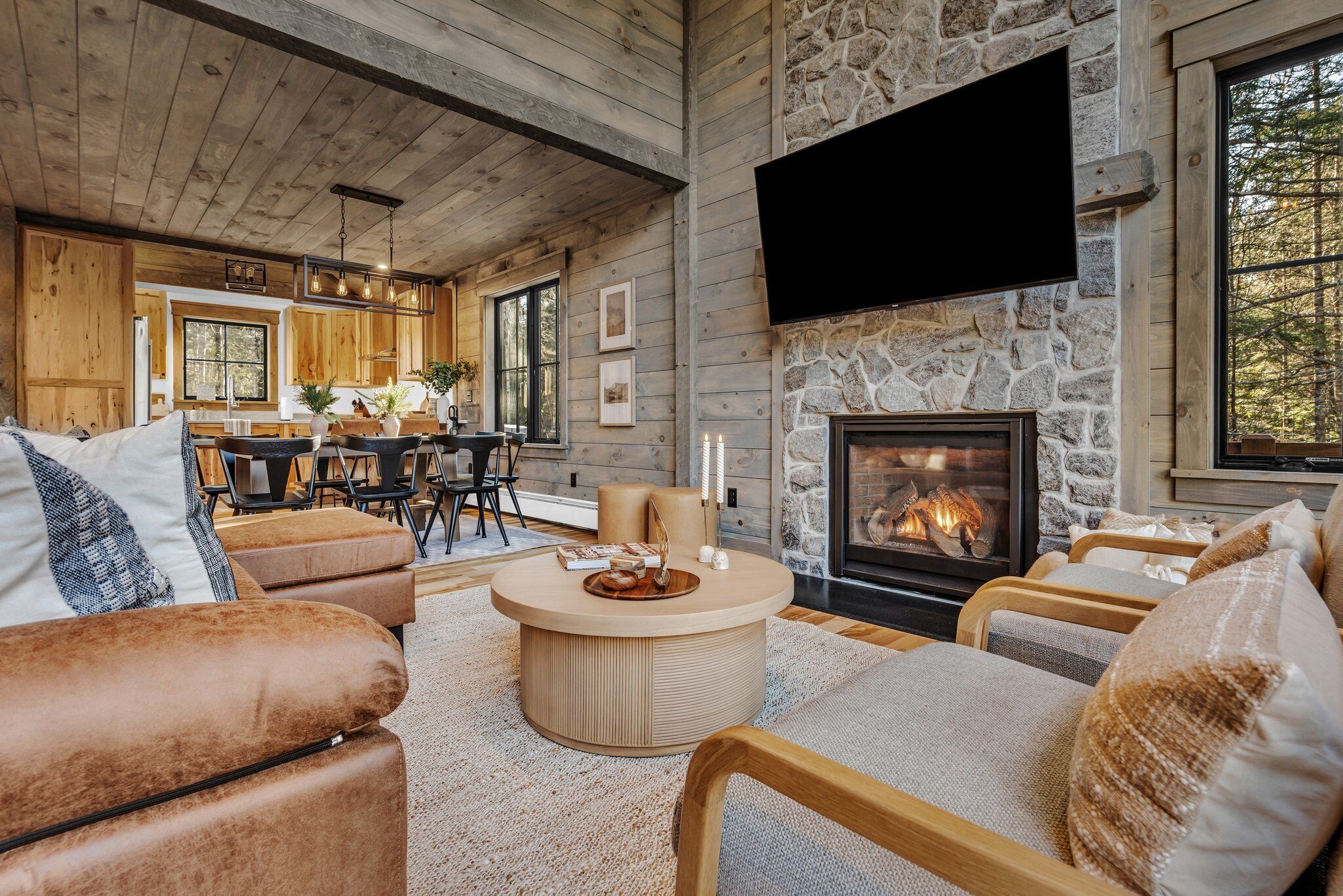 A cozy living room with a fireplace, wooden furniture, and a television mounted on the wall.