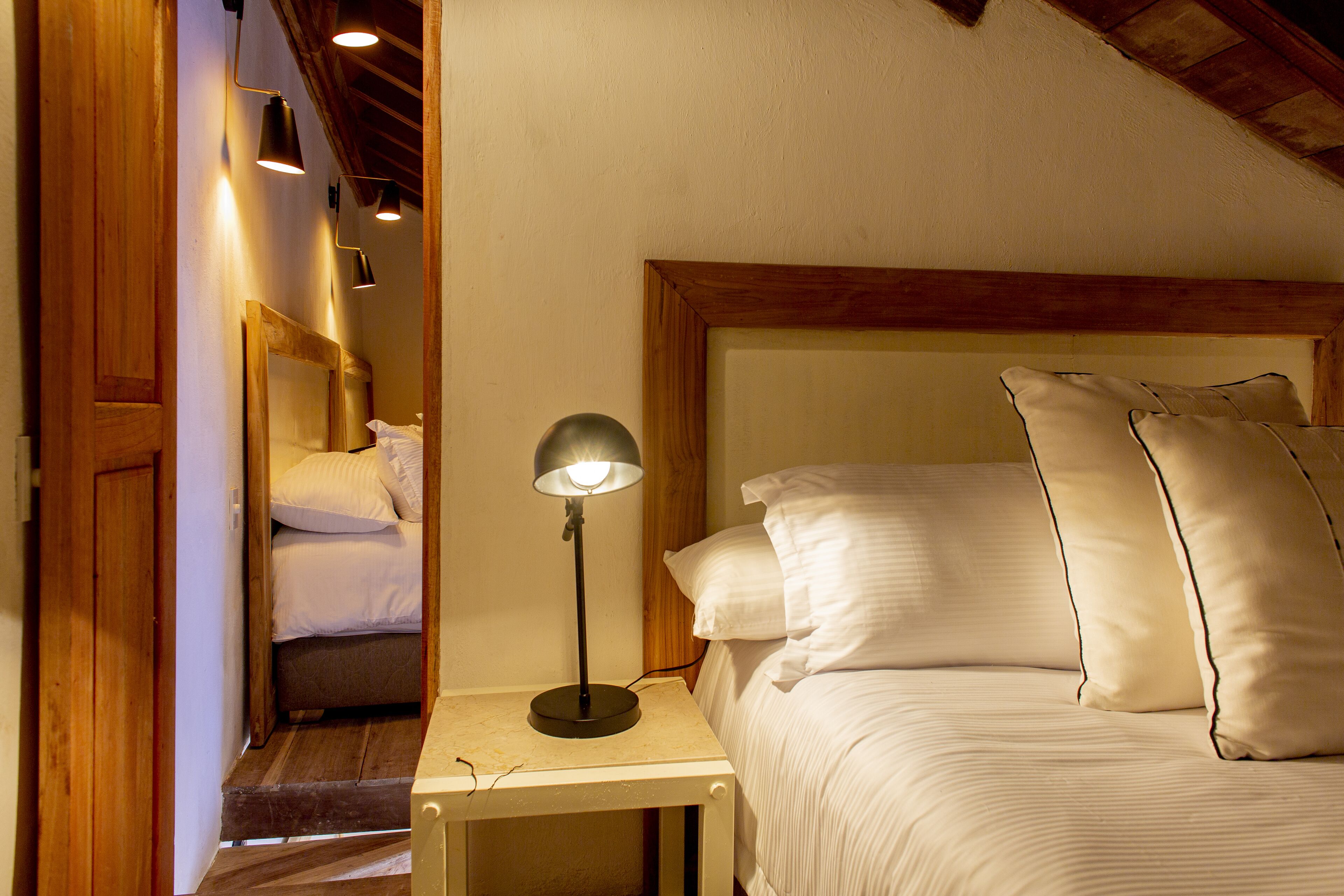 A bedroom with a bed, bedside lamp, and wooden headboard.