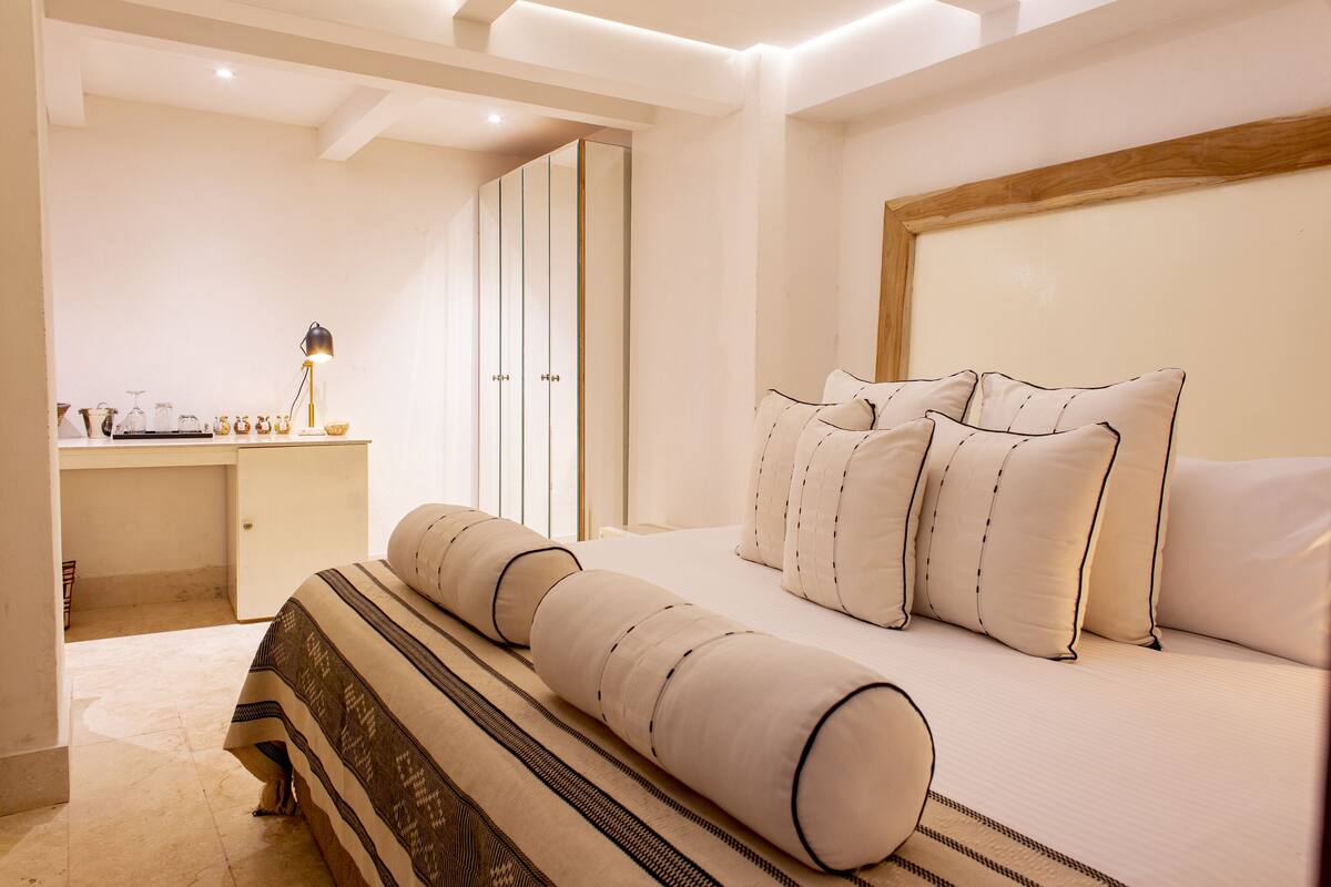 A bedroom with a bed, bedside table, lamp, and a wardrobe.