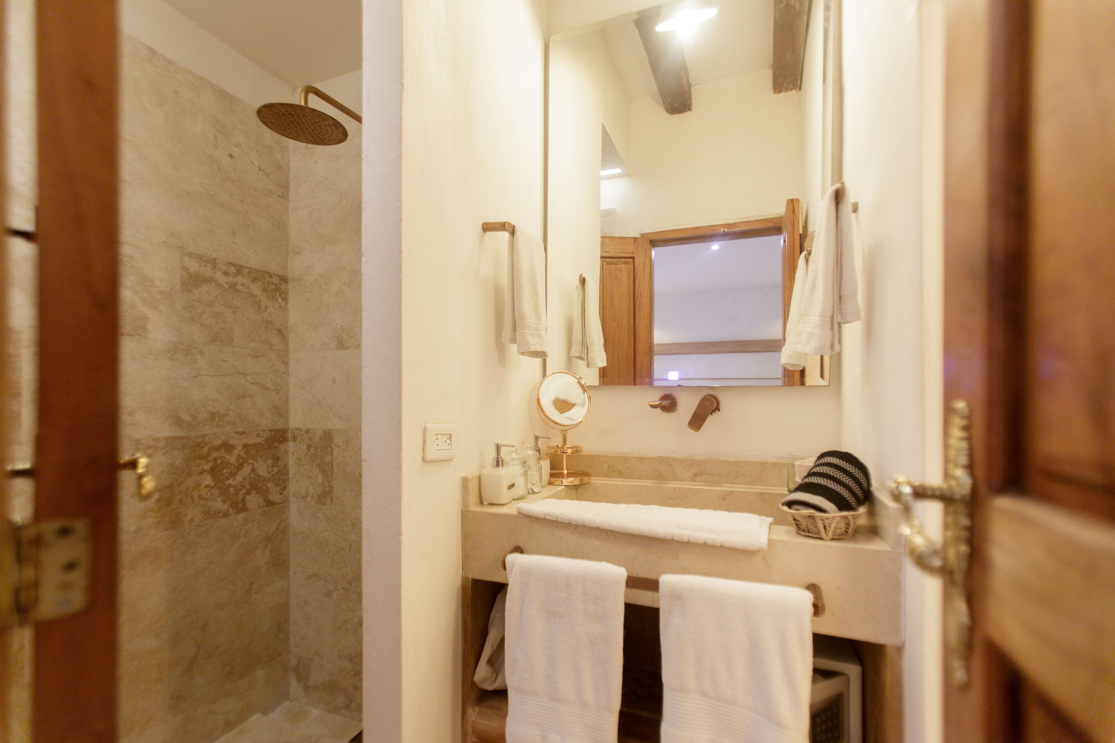 Un baño con ducha, lavamanos, espejo y toallas.