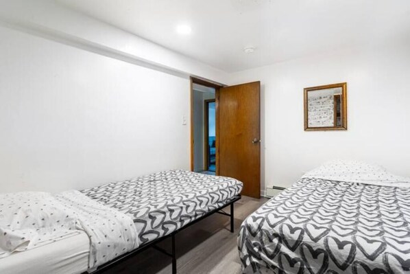 Ein Zimmer mit zwei Einzelbetten, einer Holztür und einem gerahmten Bild an der Wand.