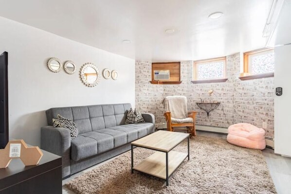 A modern living room with a grey sofa, a wooden coffee table, and a patterned rug. - Never overpay, 19 min to NYC, minutes to NYC (Newark)