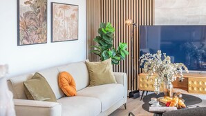 A modern living room with a sofa, cushions, a coffee table with pastries, a plant, and artwork on the wall. - Apartamento Balcón Rincón de la Victoria by Ruralidays (Málaga)