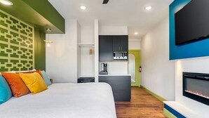 A modern hotel room with a large bed, a kitchenette, and a TV mounted on the wall. - Lake Escape @ Smoky MTN Lakeside (Dandridge)
