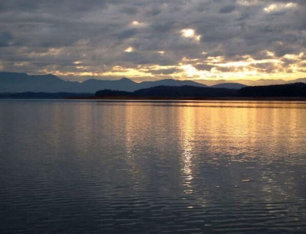 A calm lake at sunset with mountains in the background.
