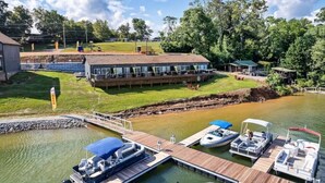 A marina with docked boats, a building with multiple windows, and a grassy area. - Lake Escape @ Smoky MTN Lakeside (Dandridge)
