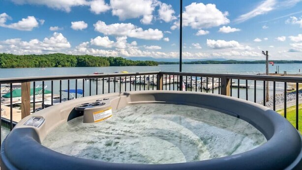 Un bain à remous sur une terrasse offrant une vue sur un lac et les bateaux amarrés.