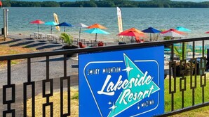 Un panneau indiquant un complexe hôtelier au bord du lac, avec une vue sur le lac et des parasols de plage.