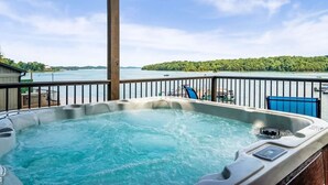 Un bain à remous sur une terrasse offrant une vue sur un lac et une île boisée.