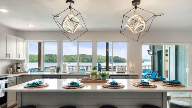 Une cuisine moderne dotée d’un grand îlot central, de tabourets de bar et offrant une vue sur un lac.