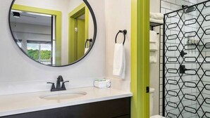 A bathroom with a round mirror, a sink, and a toilet.