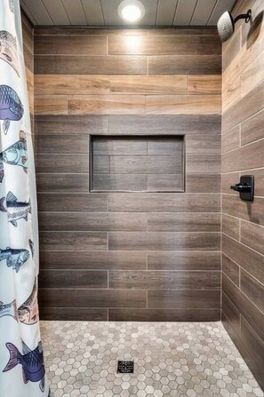 A shower area with a wooden wall design, a hexagonal tile floor, and a showerhead.
