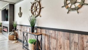 A hallway with wooden walls, a fireplace, and two ship's wheel decorations.