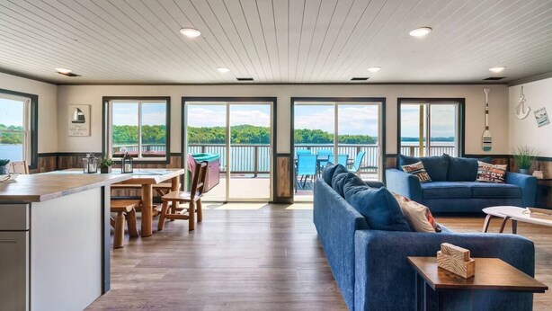 A spacious living area with a large sofa, a dining table, and a kitchen area.