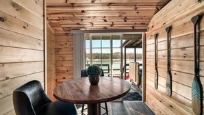 A wooden cabin interior with a round table, chairs, and a potted plant.