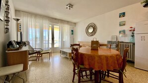 A dining area with a round table, chairs, and a kitchen in the background. - TELLINES - Appartement  avec petite vue mer (Le Grau-du-Roi)