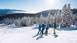 Una pista de esquí nevada con cielo despejado y una montaña al fondo.