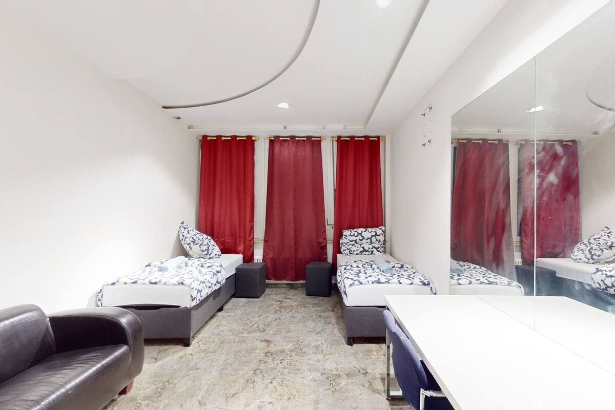 Une chambre d’hôtel avec deux lits simples, un canapé, une table et un miroir.