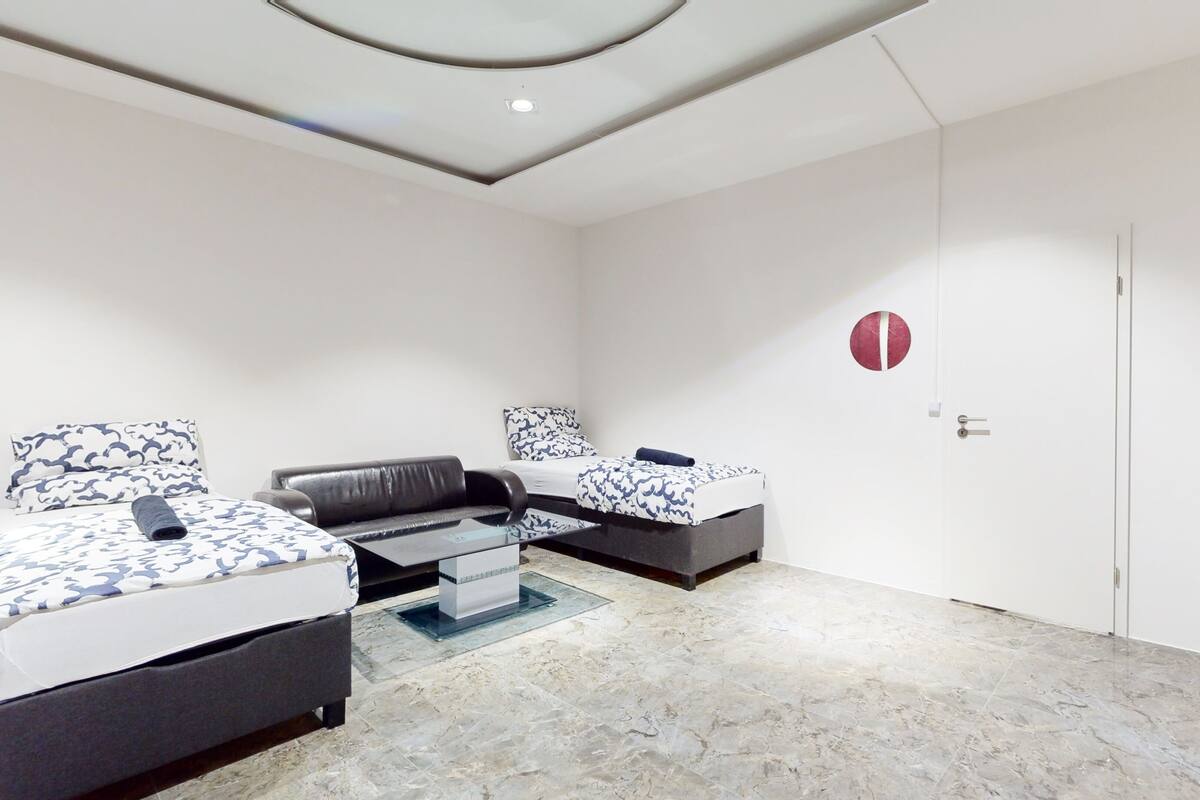 Une chambre moderne avec deux lits, un canapé et une table basse en verre.
