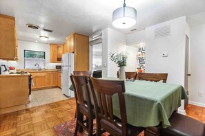 Una cocina compacta con armarios de madera, una mesa de comedor con sillas y una lámpara colgante.