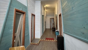 A narrow hallway with wooden walls and a wooden floor, leading to a door at the end. - Quelen Austral (Hualaihué)