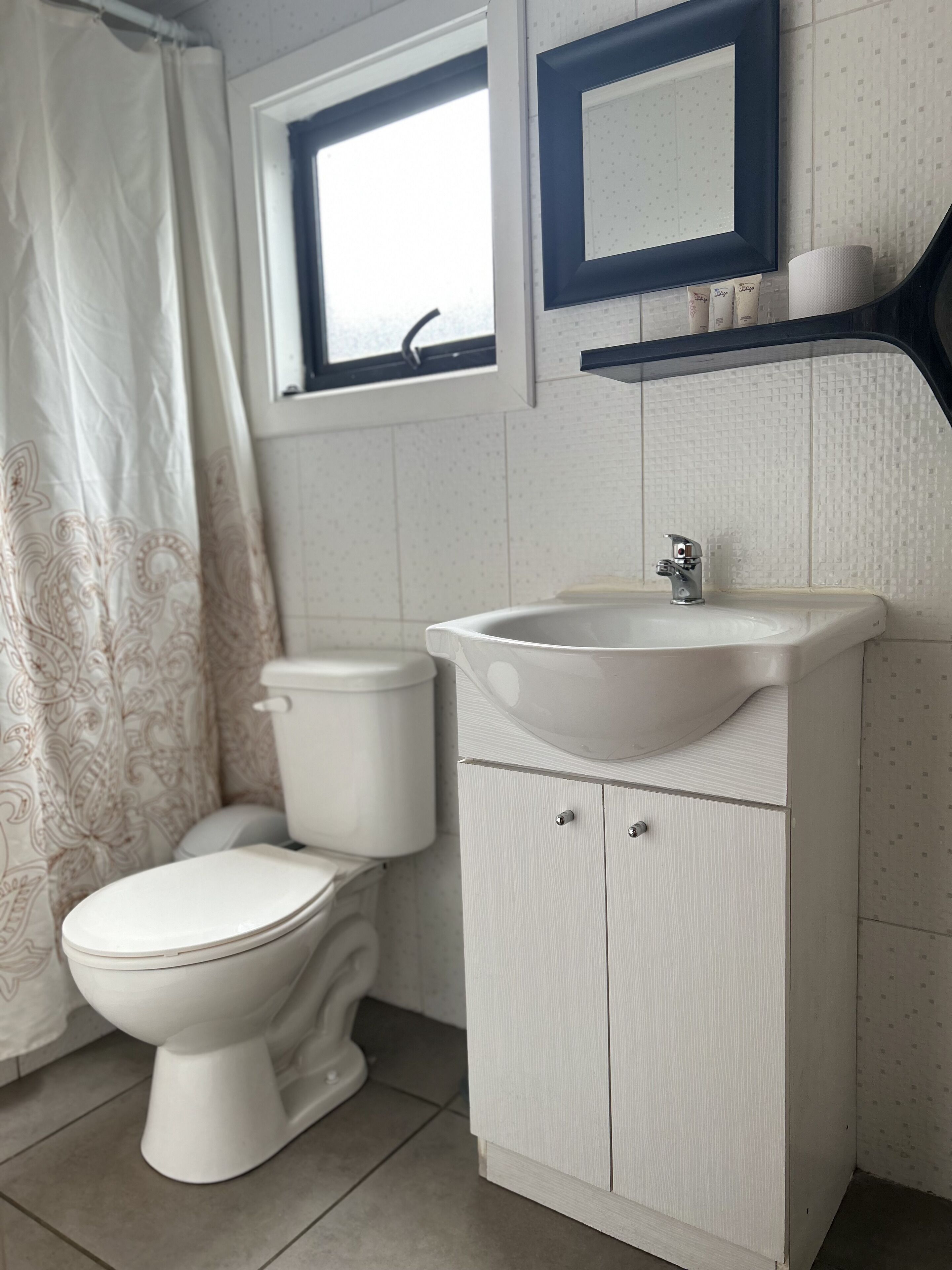 Egy fürdőszoba, amelyben WC, mosdókagyló és tükör található.