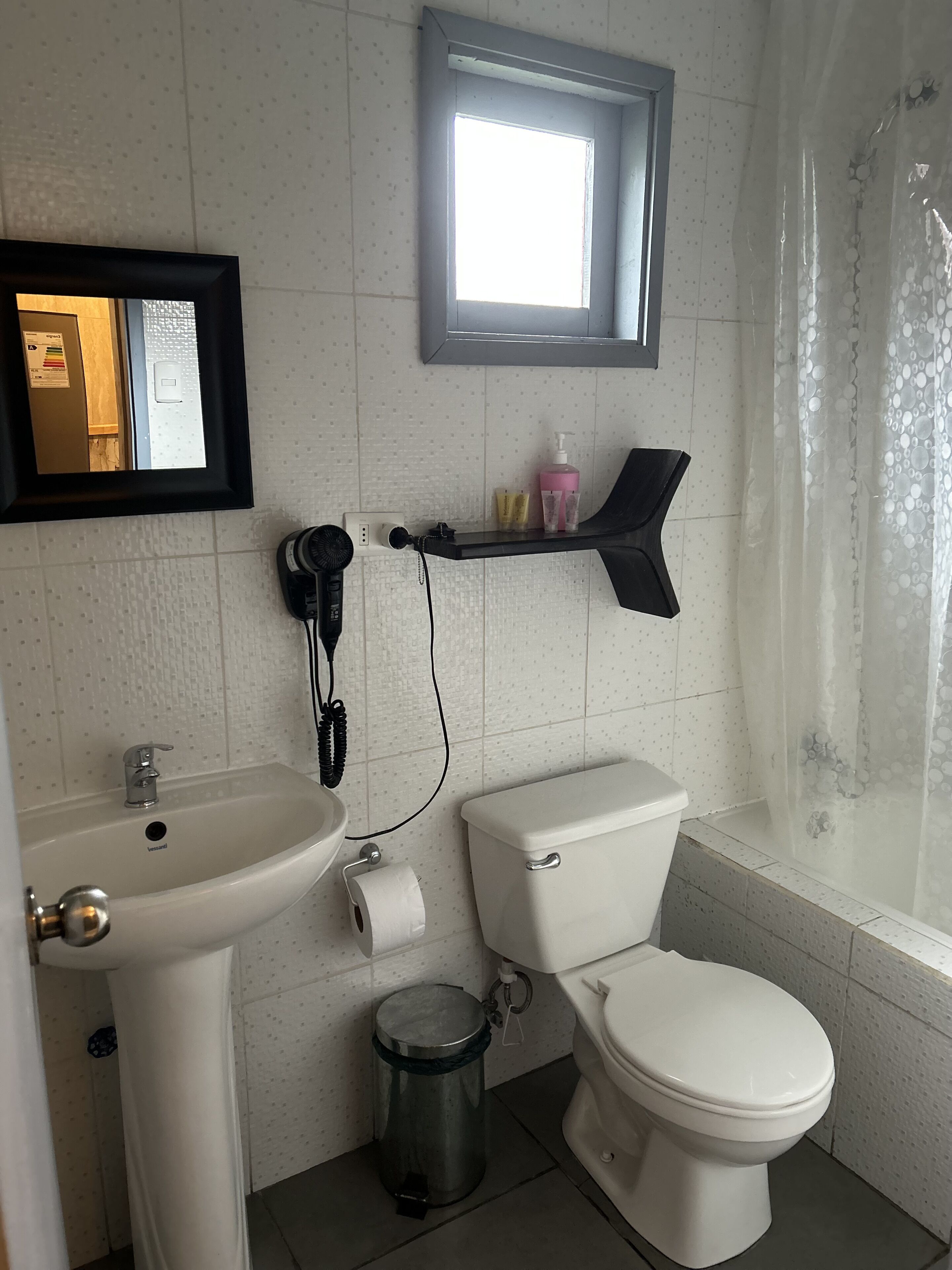 Une salle de bain avec un lavabo, des toilettes et une petite fenêtre.