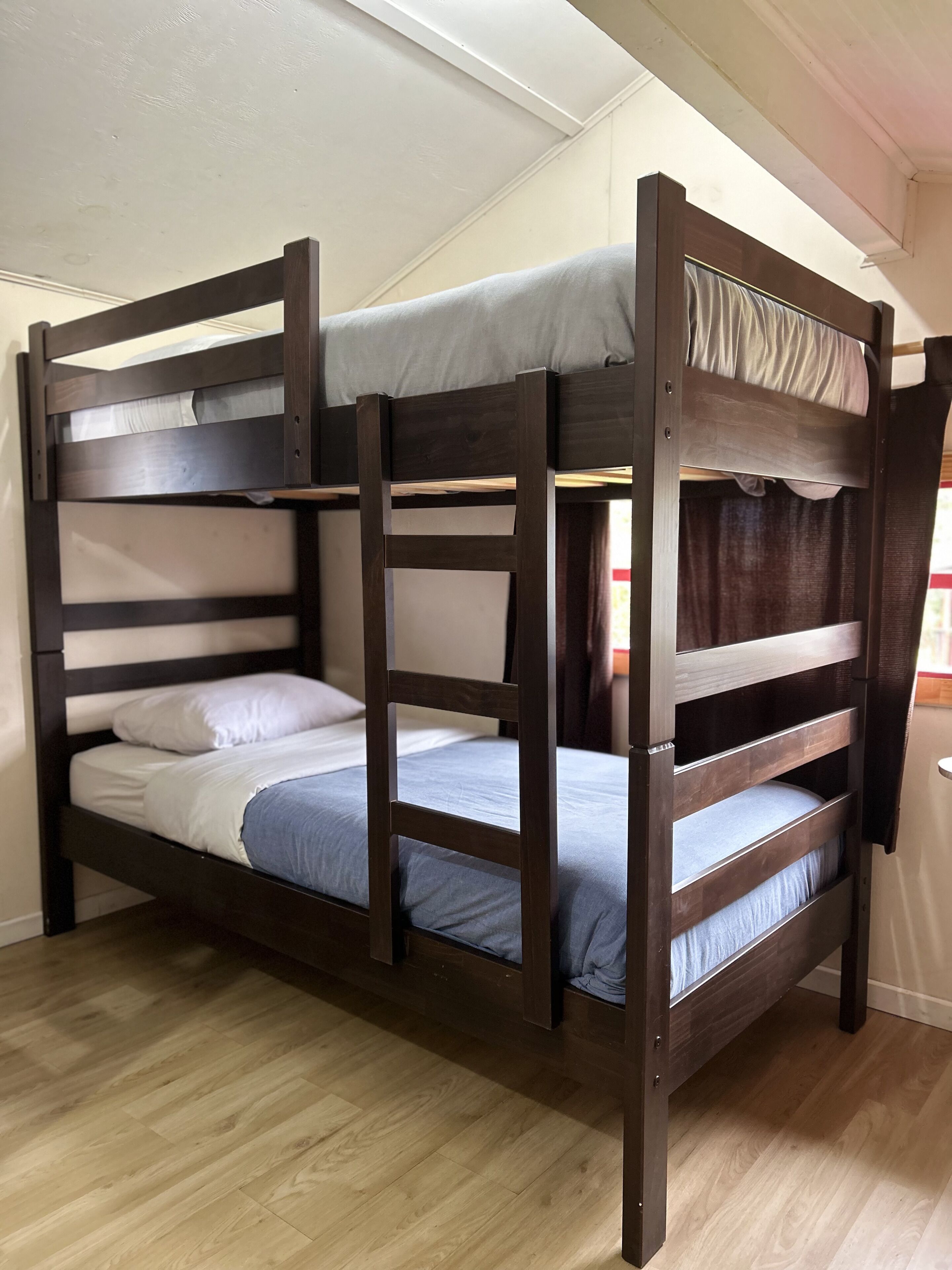 Una cama litera con estructura de madera, colchón y almohada.