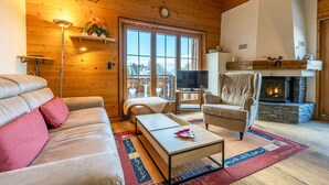 A cozy living room with a sofa, armchair, and coffee table, a fireplace, and a television.