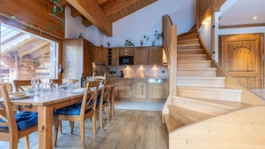 A wooden interior with a dining area, kitchen, and staircase.