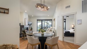 A modern dining area with a round table, two chairs, and a decorative ceiling light.