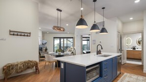 A modern kitchen with a central island, blue cabinets, and pendant lighting.