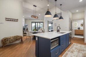 A modern kitchen with a central island, blue cabinets, and pendant lighting.