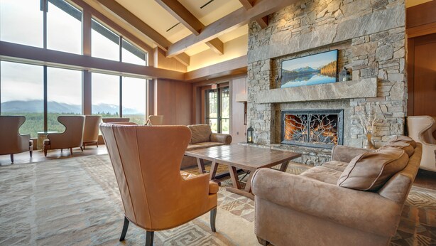 A spacious living room with a stone fireplace, leather furniture, and large windows offering mountain views. - Pet-Friendly Cle Elum Condo - Hike, Ski & Relax! (Cle Elum)